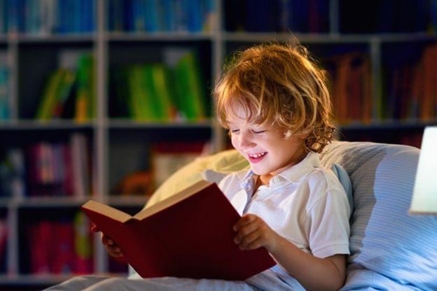 Child reading book while smiling